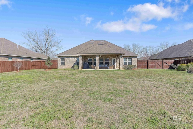 rear view of house with brick siding, a lawn, a patio, and a fenced backyard