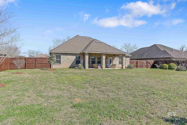 rear view of house featuring a patio, a fenced backyard, a yard, roof with shingles, and brick siding