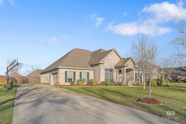 french country home featuring a front lawn, fence, concrete driveway, an attached garage, and brick siding