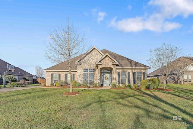 view of front of property featuring brick siding, a shingled roof, and a front lawn