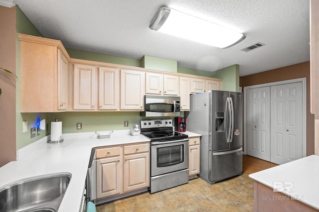 kitchen with stainless steel appliances, sink, a textured ceiling, and light brown cabinets