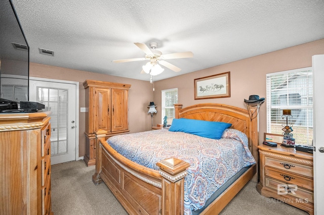 carpeted bedroom with ceiling fan and a textured ceiling