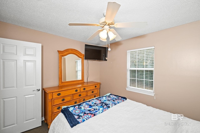 bedroom with ceiling fan and a textured ceiling