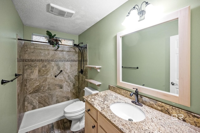 bathroom with toilet, a textured ceiling, a tile shower, vanity, and hardwood / wood-style flooring