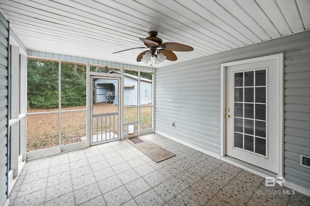 unfurnished sunroom featuring ceiling fan