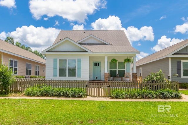 view of front of house with a fenced front yard, a shingled roof, covered porch, board and batten siding, and a front yard