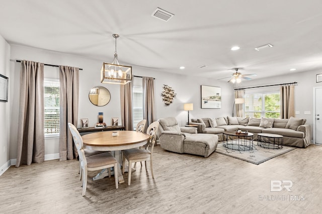 living room featuring light wood finished floors, recessed lighting, visible vents, baseboards, and ceiling fan with notable chandelier