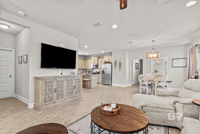 living room featuring light wood finished floors, baseboards, visible vents, and recessed lighting