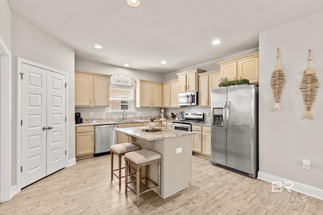 kitchen with a center island, a breakfast bar, stainless steel appliances, a sink, and light wood-type flooring