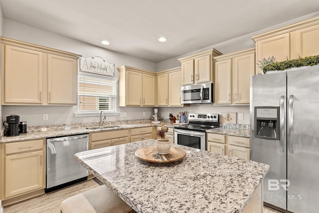 kitchen featuring recessed lighting, a sink, appliances with stainless steel finishes, cream cabinetry, and light stone countertops