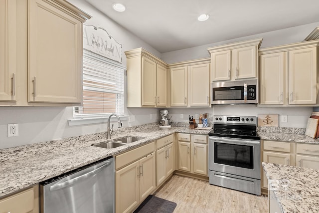kitchen with cream cabinetry, stainless steel appliances, recessed lighting, a sink, and light wood-type flooring