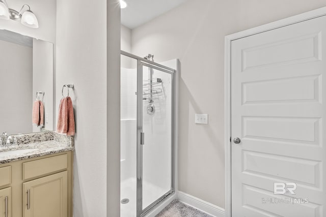 full bath featuring baseboards, a shower stall, and vanity