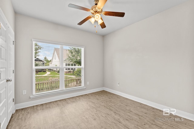 empty room with a ceiling fan, light wood-style flooring, and baseboards