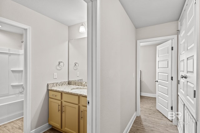 full bathroom featuring bathtub / shower combination, vanity, baseboards, and wood finished floors