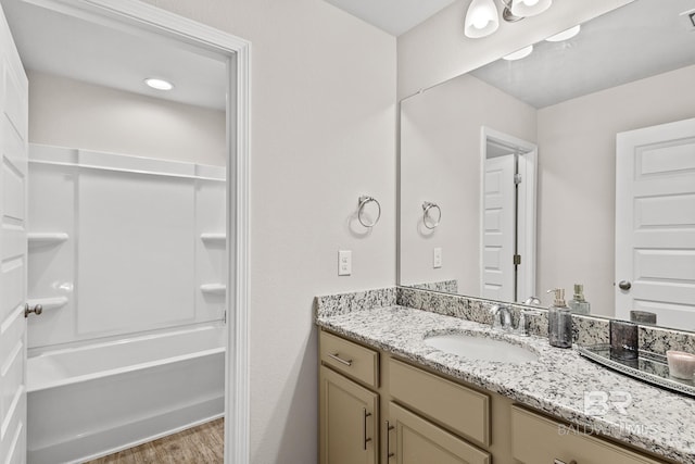 bathroom with washtub / shower combination, visible vents, wood finished floors, and vanity