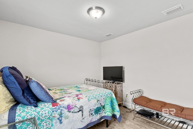 bedroom with baseboards, visible vents, and wood finished floors