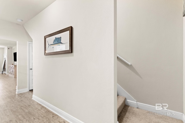hallway featuring stairway, light wood-type flooring, and baseboards