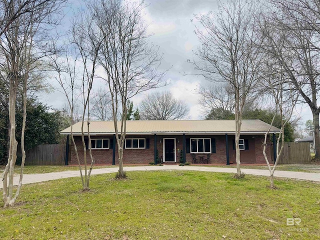 ranch-style house featuring driveway, fence, a front lawn, and brick siding