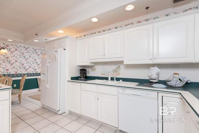 kitchen featuring white appliances, white cabinets, sink, a raised ceiling, and ornamental molding