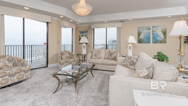 living room with crown molding, carpet, a notable chandelier, and a tray ceiling