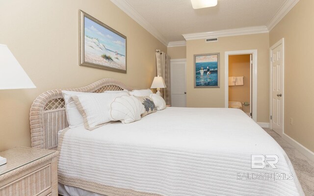 carpeted bedroom featuring ensuite bath and ornamental molding