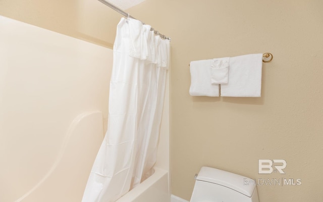 bathroom featuring shower / bath combination with curtain and toilet