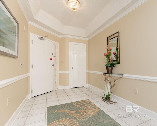 foyer entrance featuring ornamental molding, light tile floors, a tray ceiling, and a textured ceiling