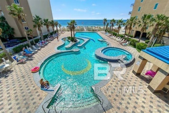 view of pool featuring a water view and a pool with connected hot tub