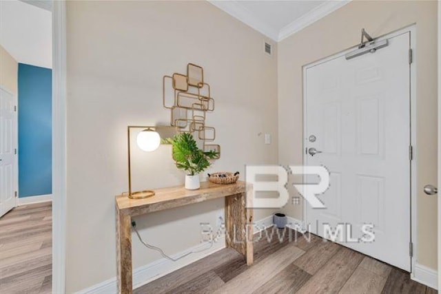 foyer entrance featuring ornamental molding, wood finished floors, visible vents, and baseboards