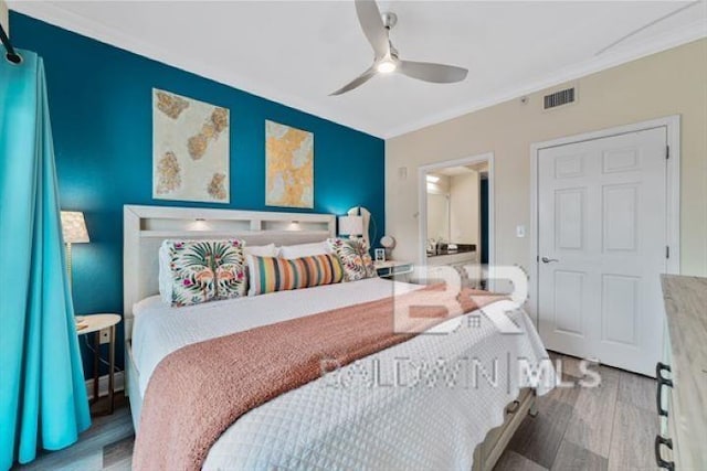 bedroom with ceiling fan, ornamental molding, wood finished floors, and visible vents