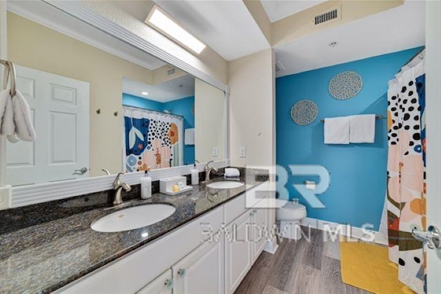 bathroom featuring double vanity, visible vents, a sink, and wood finished floors