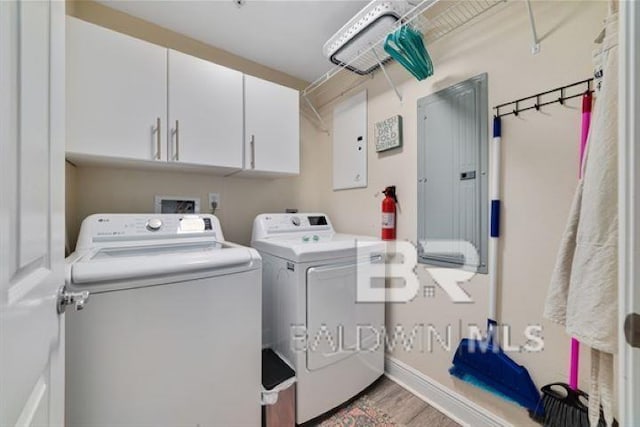 laundry room with cabinet space, washing machine and dryer, electric panel, and light wood finished floors