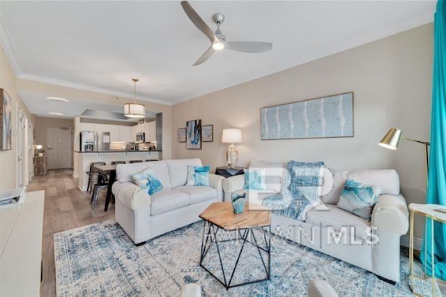 living area featuring light wood-style floors, ceiling fan, and ornamental molding