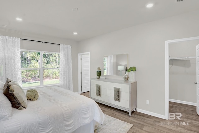 bedroom featuring wood-type flooring and a walk in closet