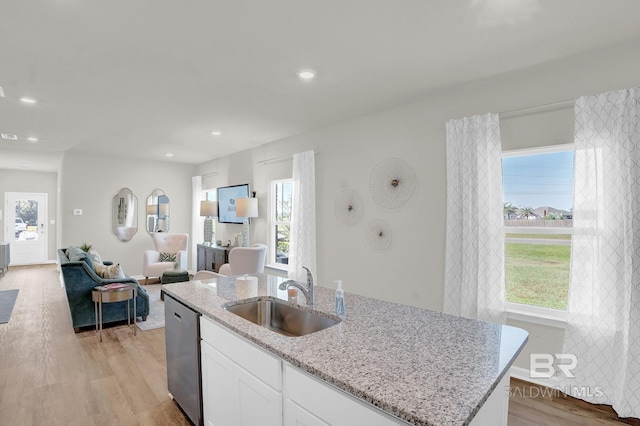 kitchen with white cabinets, stainless steel dishwasher, light wood-type flooring, and sink