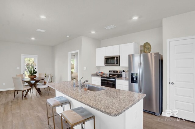 kitchen featuring light wood-type flooring, a breakfast bar, stainless steel appliances, sink, and an island with sink