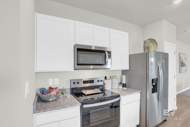 kitchen with light stone counters, white cabinetry, appliances with stainless steel finishes, and light hardwood / wood-style flooring