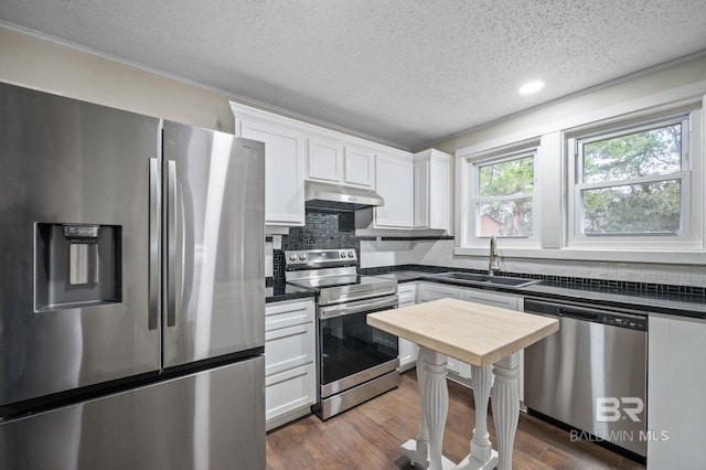 kitchen with sink, dark wood-type flooring, white cabinets, exhaust hood, and appliances with stainless steel finishes