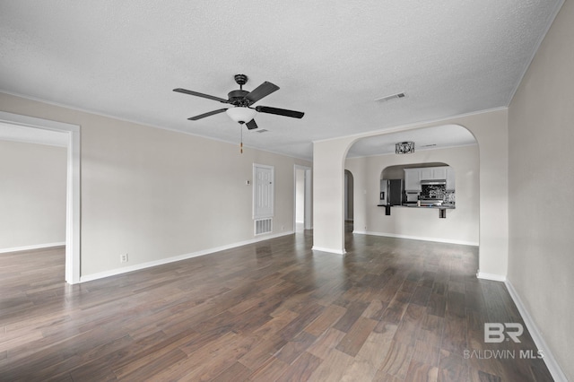 unfurnished living room with ceiling fan, dark hardwood / wood-style flooring, a textured ceiling, and crown molding