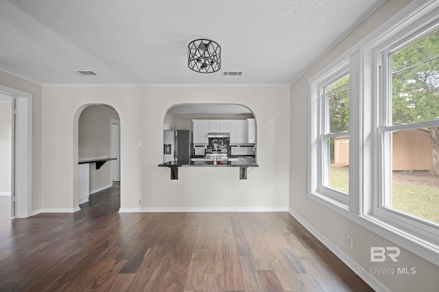 living room featuring crown molding, dark hardwood / wood-style flooring, and a textured ceiling