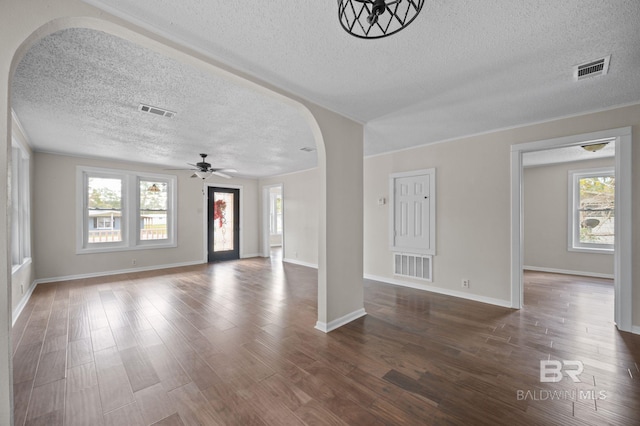 unfurnished living room with dark hardwood / wood-style flooring, a healthy amount of sunlight, and a textured ceiling