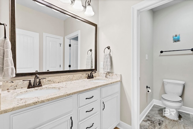 full bath featuring baseboards, a sink, toilet, and double vanity