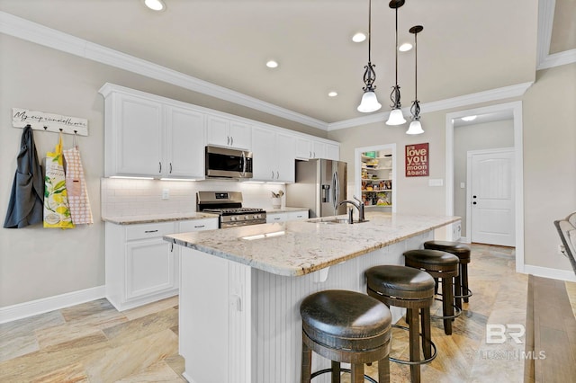 kitchen featuring crown molding, a breakfast bar area, stainless steel appliances, a sink, and an island with sink