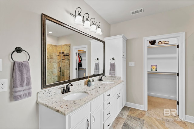 full bath featuring a stall shower, a sink, visible vents, and a walk in closet