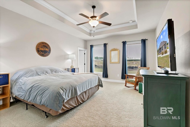 bedroom featuring ceiling fan, light colored carpet, baseboards, ornamental molding, and a tray ceiling