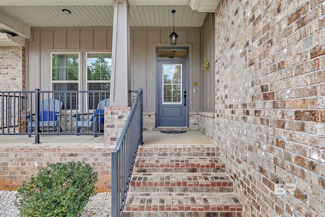 doorway to property featuring brick siding and a porch