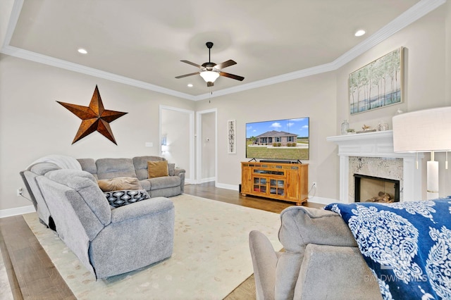 living room with crown molding, a fireplace, baseboards, and wood finished floors