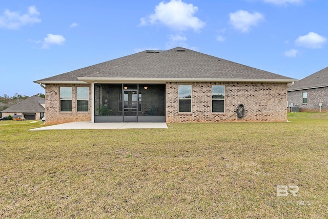 rear view of house featuring a sunroom, a patio area, a yard, and brick siding