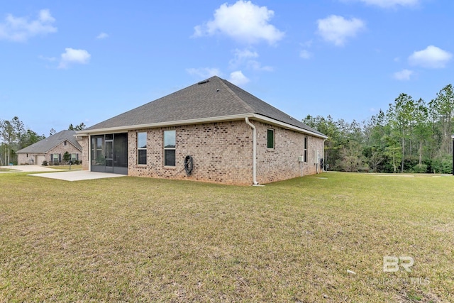 back of house with roof with shingles, brick siding, a yard, a patio, and a sunroom