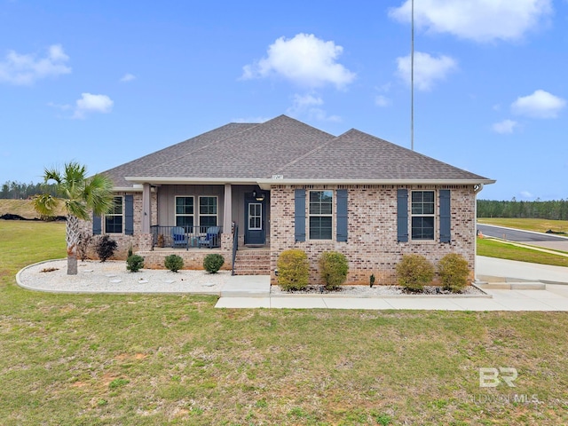 view of front of home featuring covered porch, brick siding, a front lawn, and roof with shingles